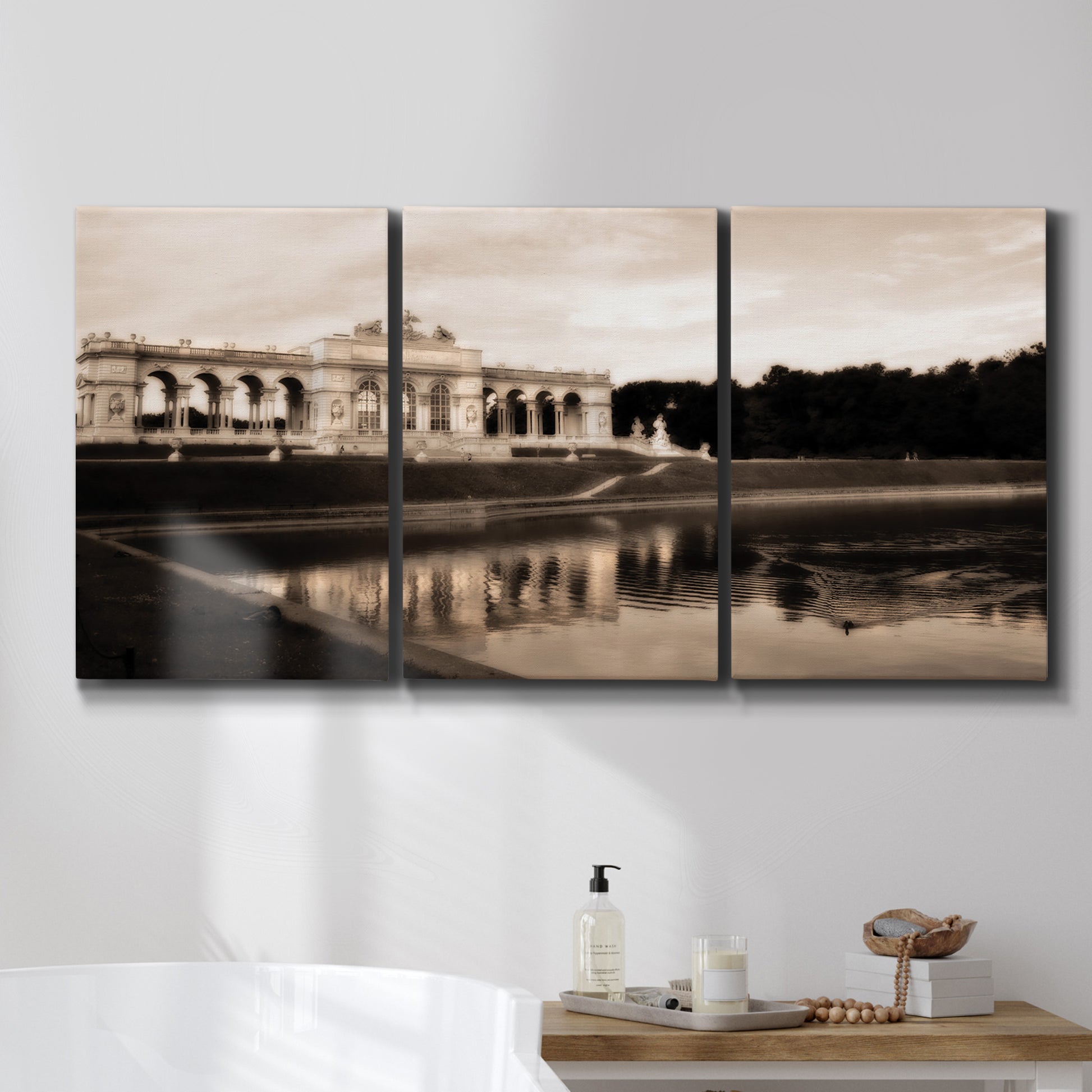 Three-panel canvas wall art featuring monochrome historic pavilion photograph, displayed in a bathroom above a bathtub.