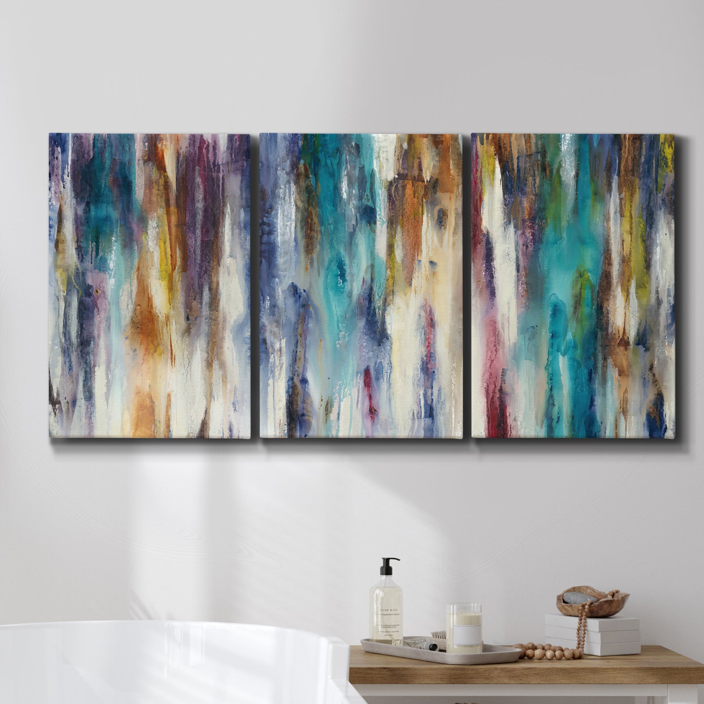 Three-panel canvas wall art featuring abstract shifting color forms, displayed in a bathroom above a bathtub.