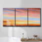 Three-panel canvas wall art featuring glowing sunset sky over landscape, displayed in a bathroom above a bathtub.