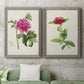 Set of two gray barnwood framed canvas prints depicting a coordinated art pair of pink flowering plant specimens rendered as vintage botanical plate illustrations above a sofa in a modern living room.