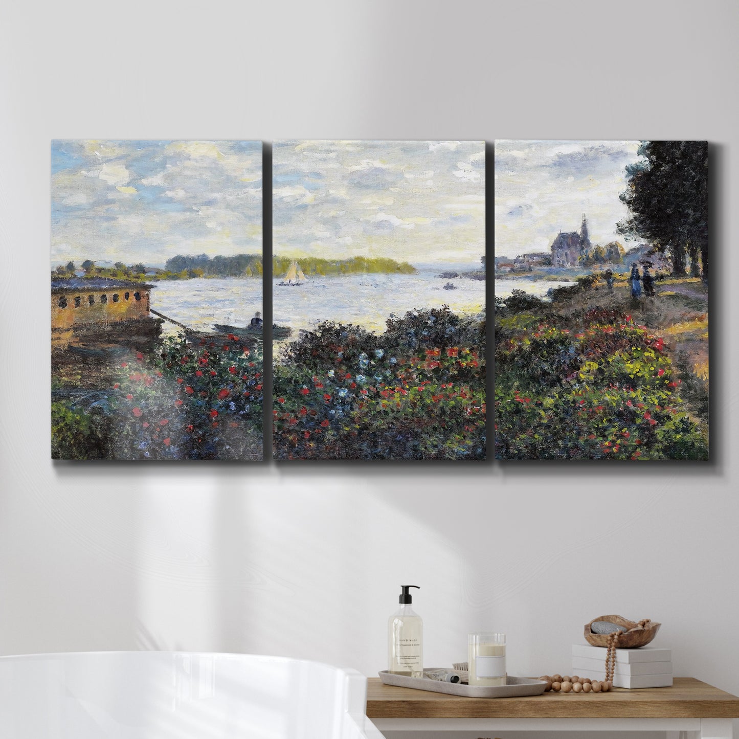 Three-panel canvas wall art featuring river with boats and shoreline, displayed in a bathroom above a bathtub.