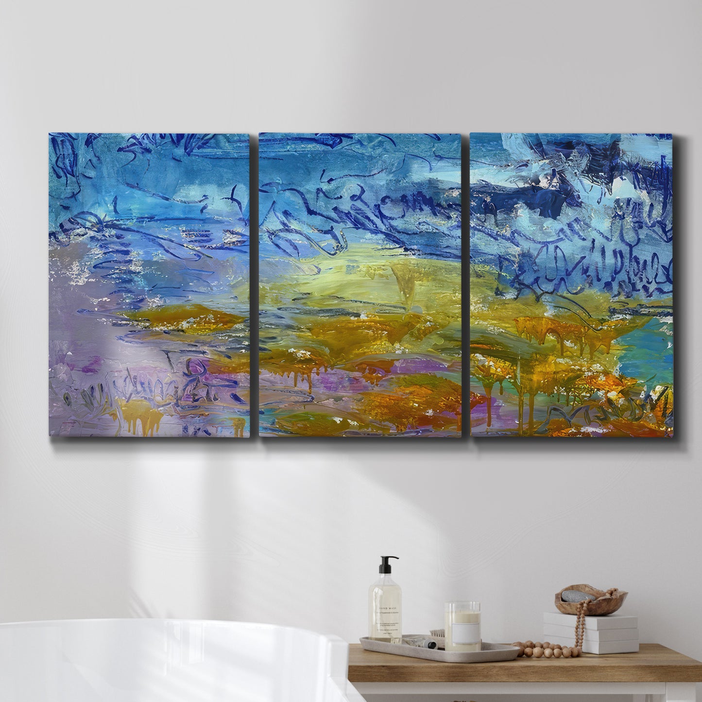 Three-panel canvas wall art featuring expressive abstract with layered color, displayed in a bathroom above a bathtub.