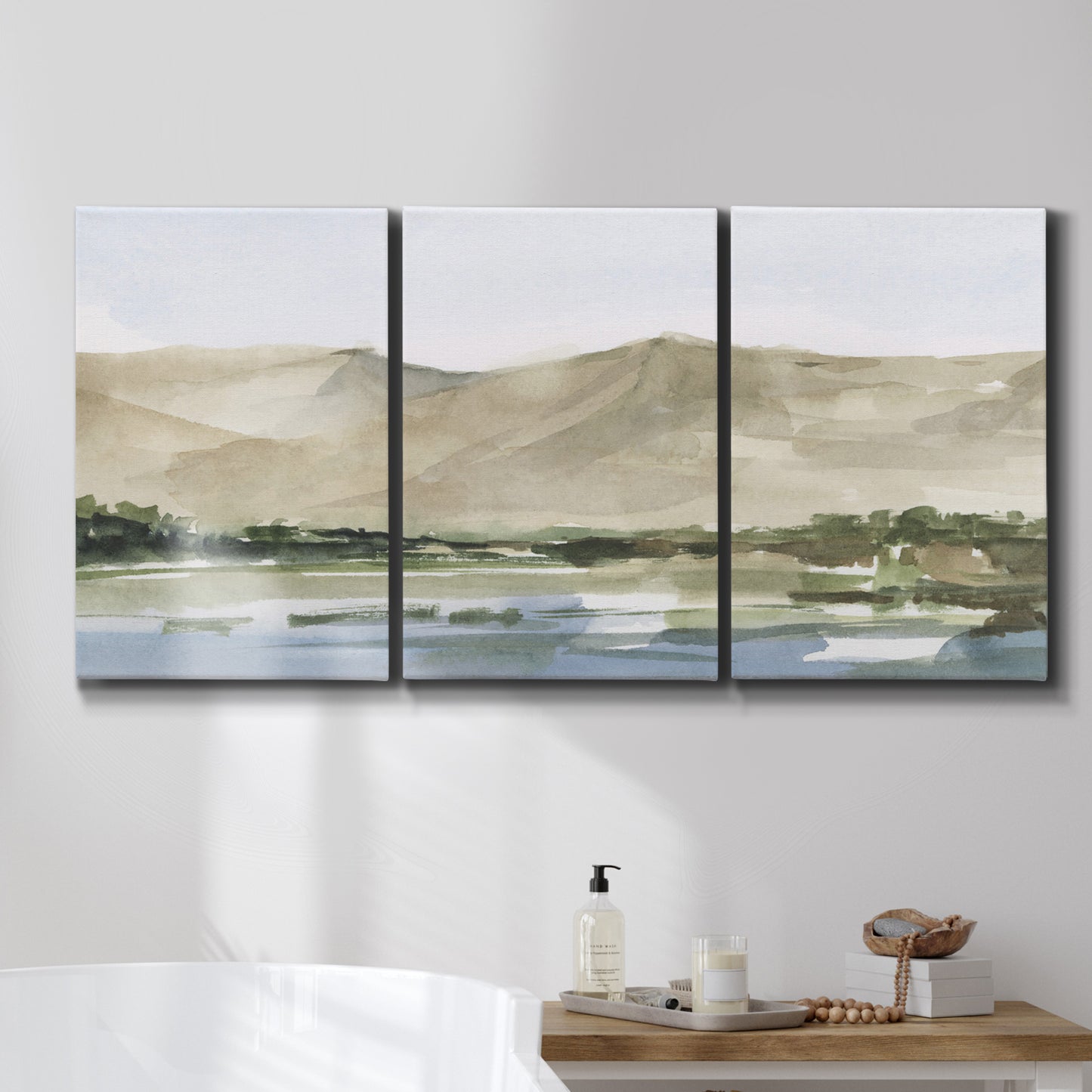 Three-panel canvas wall art featuring desert mountain landscape watercolor, displayed in a bathroom above a bathtub.