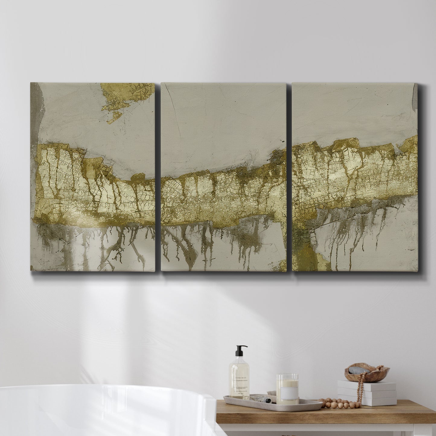 Three-panel canvas wall art featuring gold accented abstract ravine, displayed in a bathroom above a bathtub.