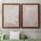 Set of two maple barnwood framed canvas prints depicting a coordinated art pair of soft blush and white painterly fields rendered as minimalist color-field abstracts above a sofa in a modern living room.