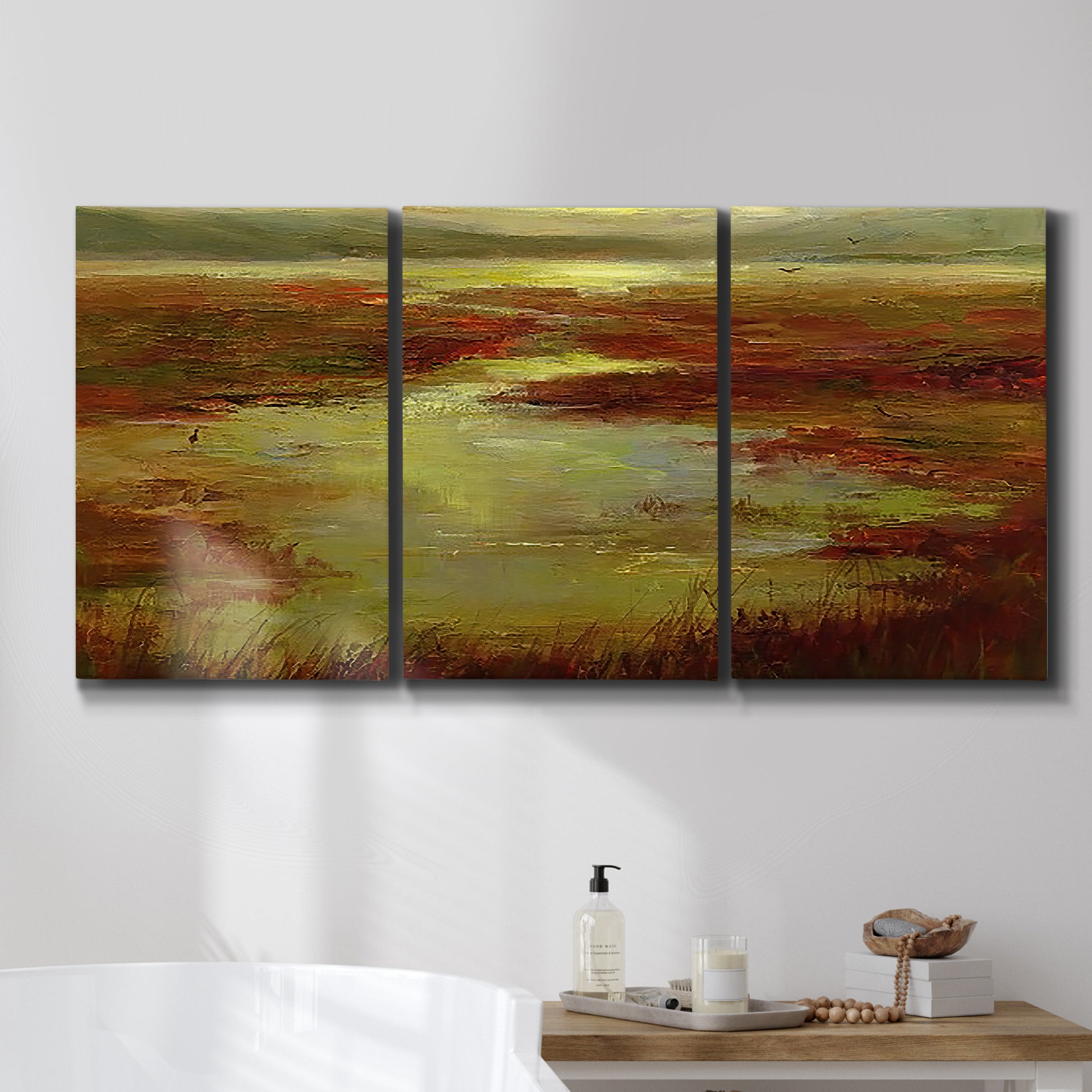 Three-panel canvas wall art featuring coastal shoreline with warm light, displayed in a bathroom above a bathtub.