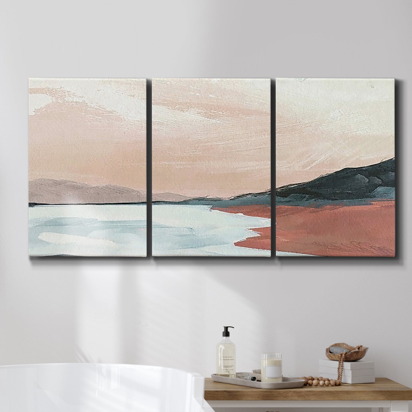 Three-panel canvas wall art featuring quiet coastline with distant horizon, displayed in a bathroom above a bathtub.