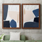 Set of two maple barnwood framed canvas prints depicting a coordinated art pair of large navy cream and beige organic geometric shapes rendered as minimalist color-block abstracts above a sofa in a modern living room.