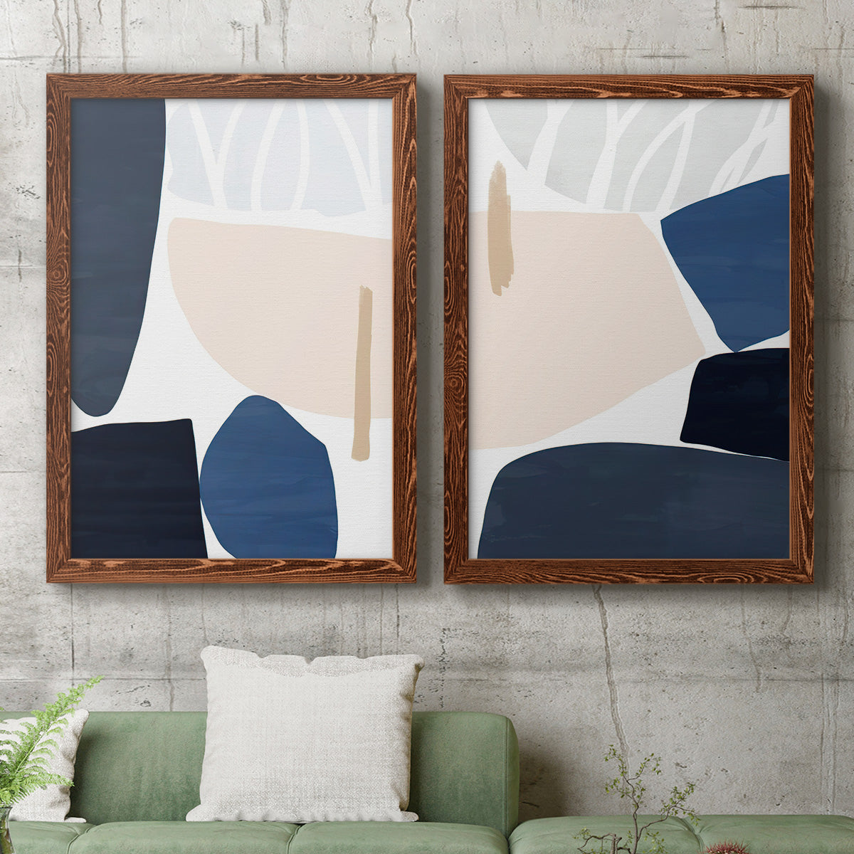 Set of two maple barnwood framed canvas prints depicting a coordinated art pair of large navy cream and beige organic geometric shapes rendered as minimalist color-block abstracts above a sofa in a modern living room.