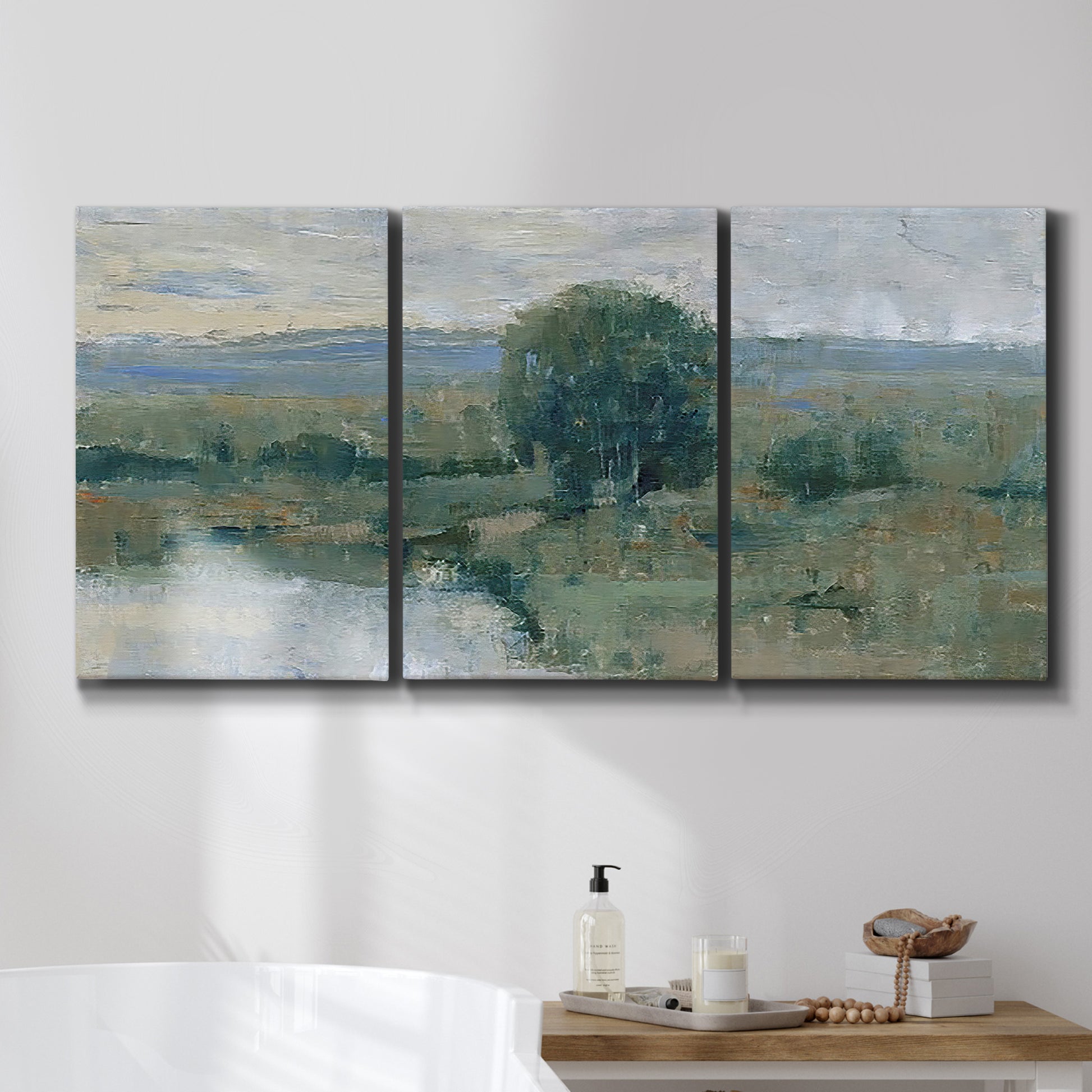 Three-panel canvas wall art featuring riverbank landscape with reflections, displayed in a bathroom above a bathtub.