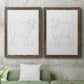 Set of two walnut barnwood framed canvas prints depicting a coordinated art pair of simple contour drawings of standing cows rendered as minimalist livestock sketches above a sofa in a modern living room.
