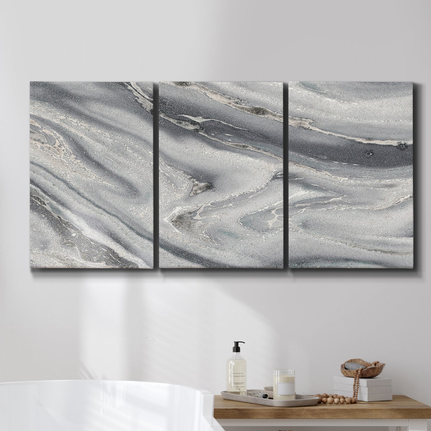 Three-panel canvas wall art featuring minimal monochrome abstract forms, displayed in a bathroom above a bathtub.