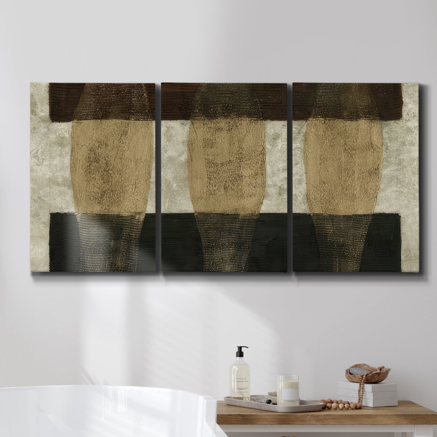 Three-panel canvas wall art featuring textured abstract vessel forms, displayed in a bathroom above a bathtub.