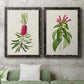 Set of two black barnwood framed canvas prints depicting a coordinated art pair of pink flowering plant specimens rendered as vintage botanical plate illustrations above a sofa in a modern living room.