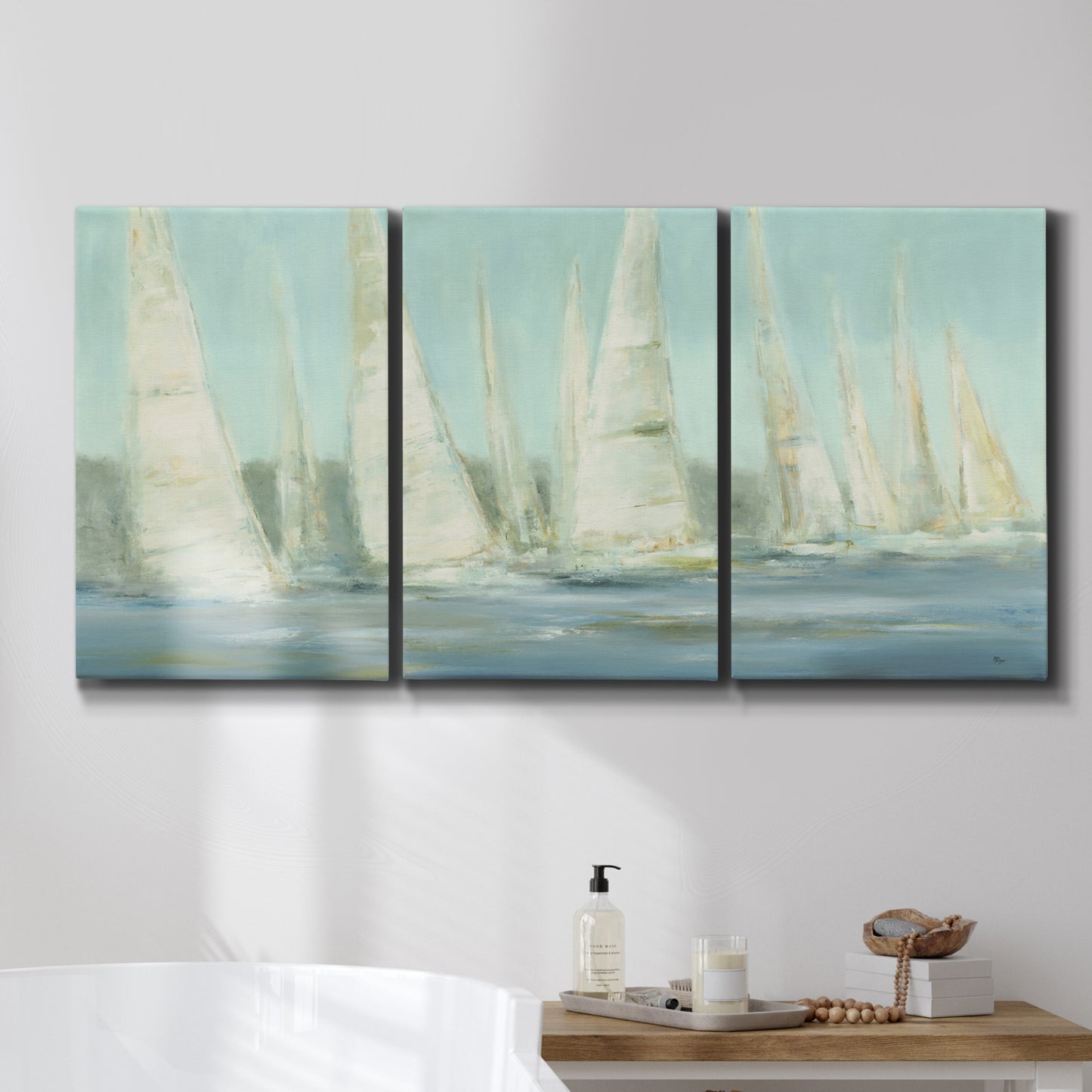 Three-panel canvas wall art featuring sailboats silhouetted at sunrise, displayed in a bathroom above a bathtub.