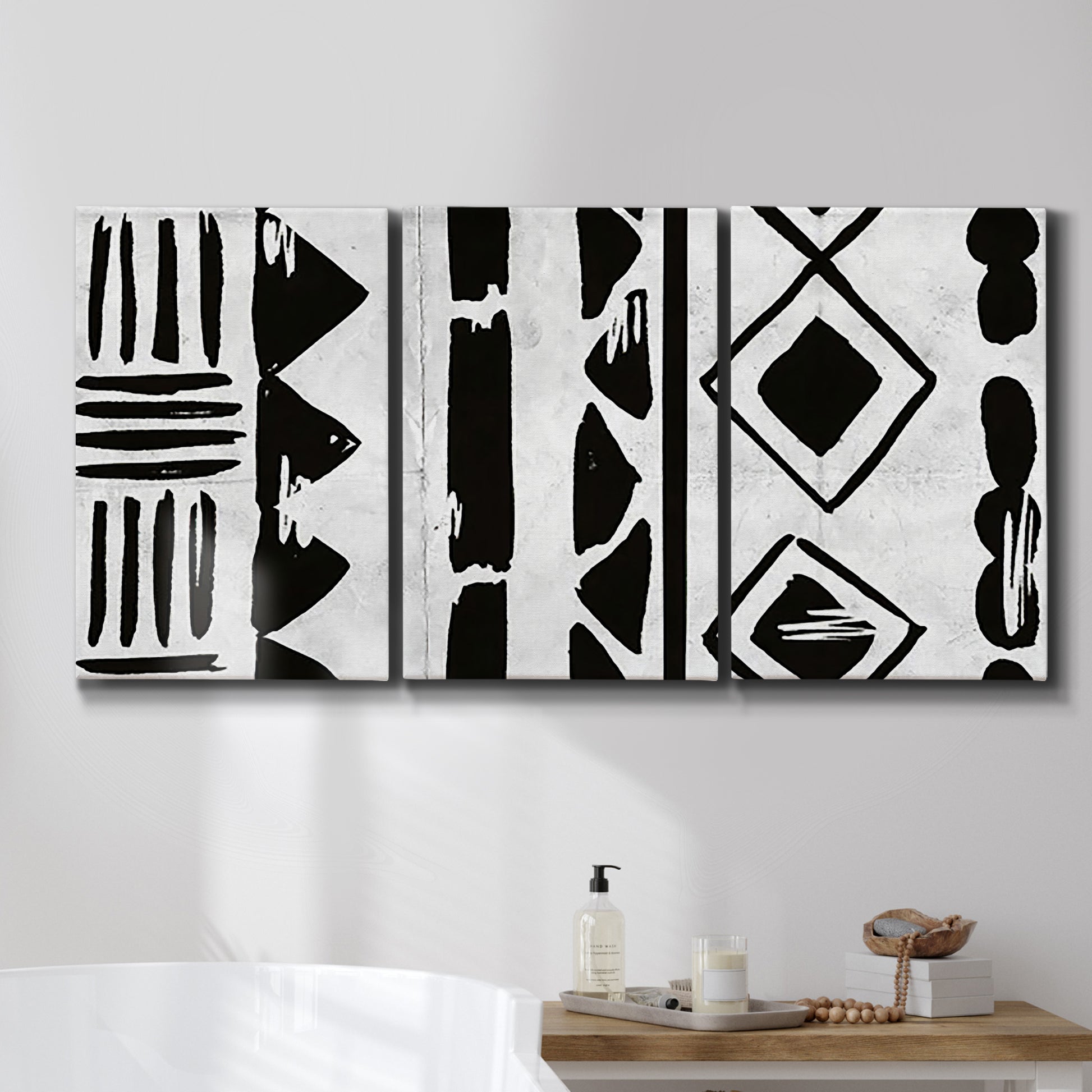 Three-panel canvas wall art featuring geometric abstract forms merging pattern, displayed in a bathroom above a bathtub.