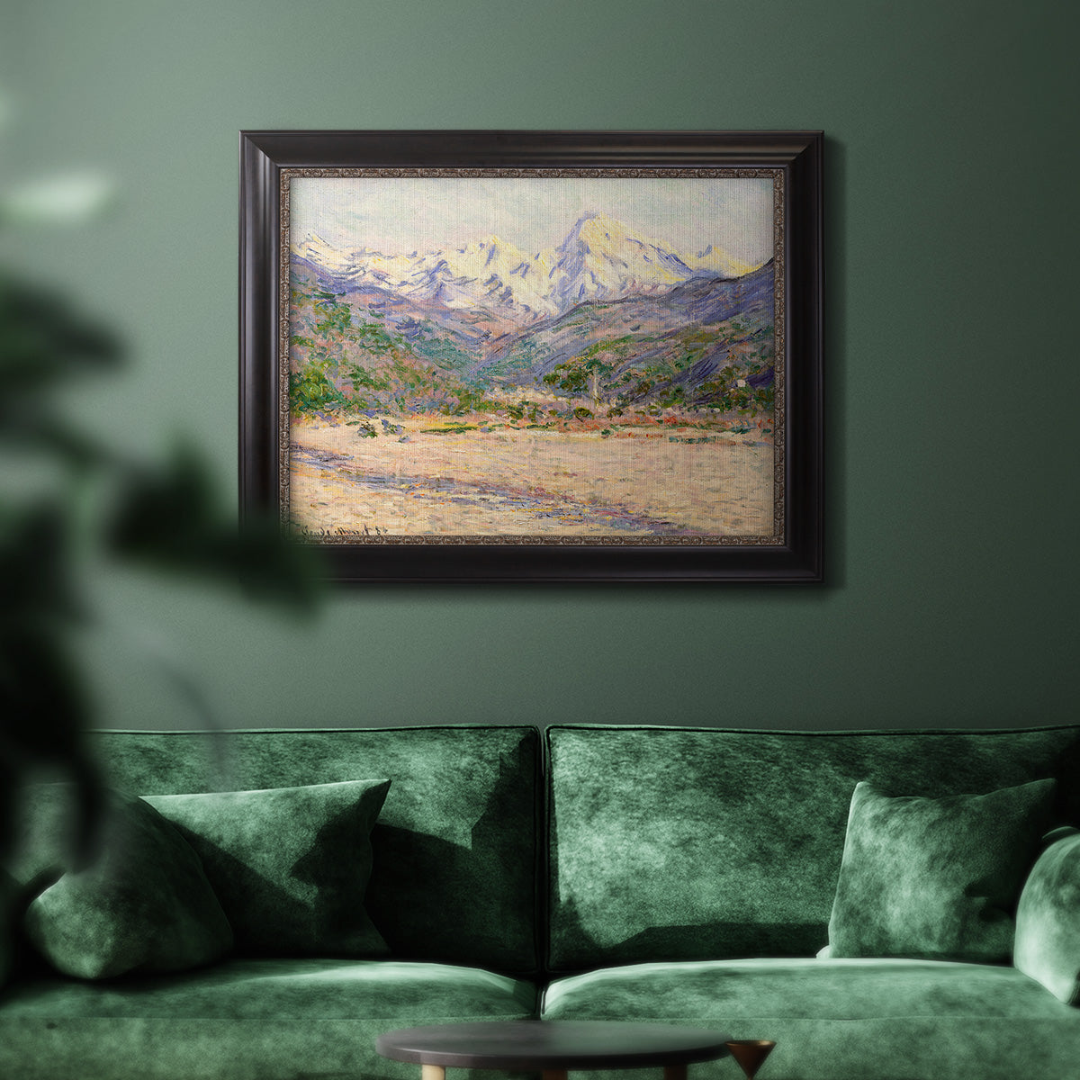 Impressionist valley landscape in southern France by Claude Monet in an ornate black frame with gilded inner detail displayed in a dark-toned interior setting.