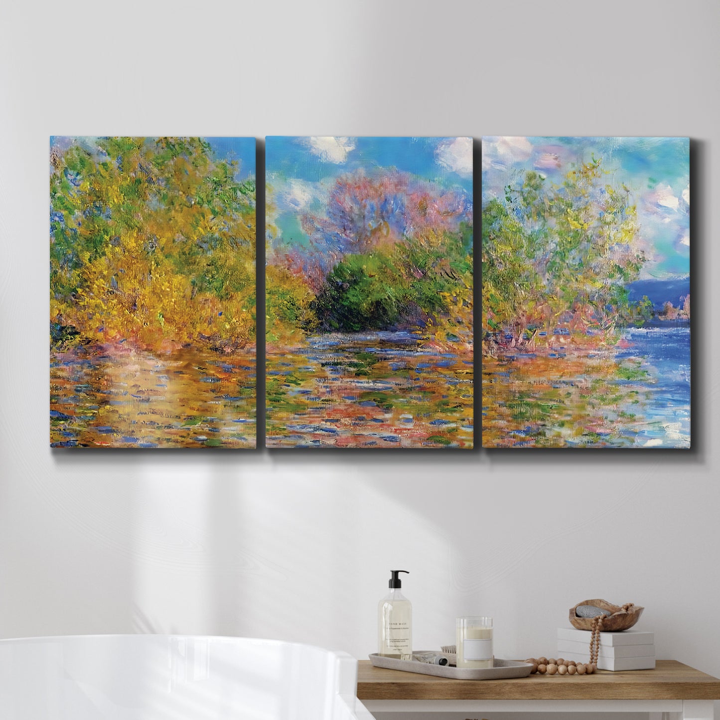 Three-panel canvas wall art featuring wide river landscape, displayed in a bathroom above a bathtub.
