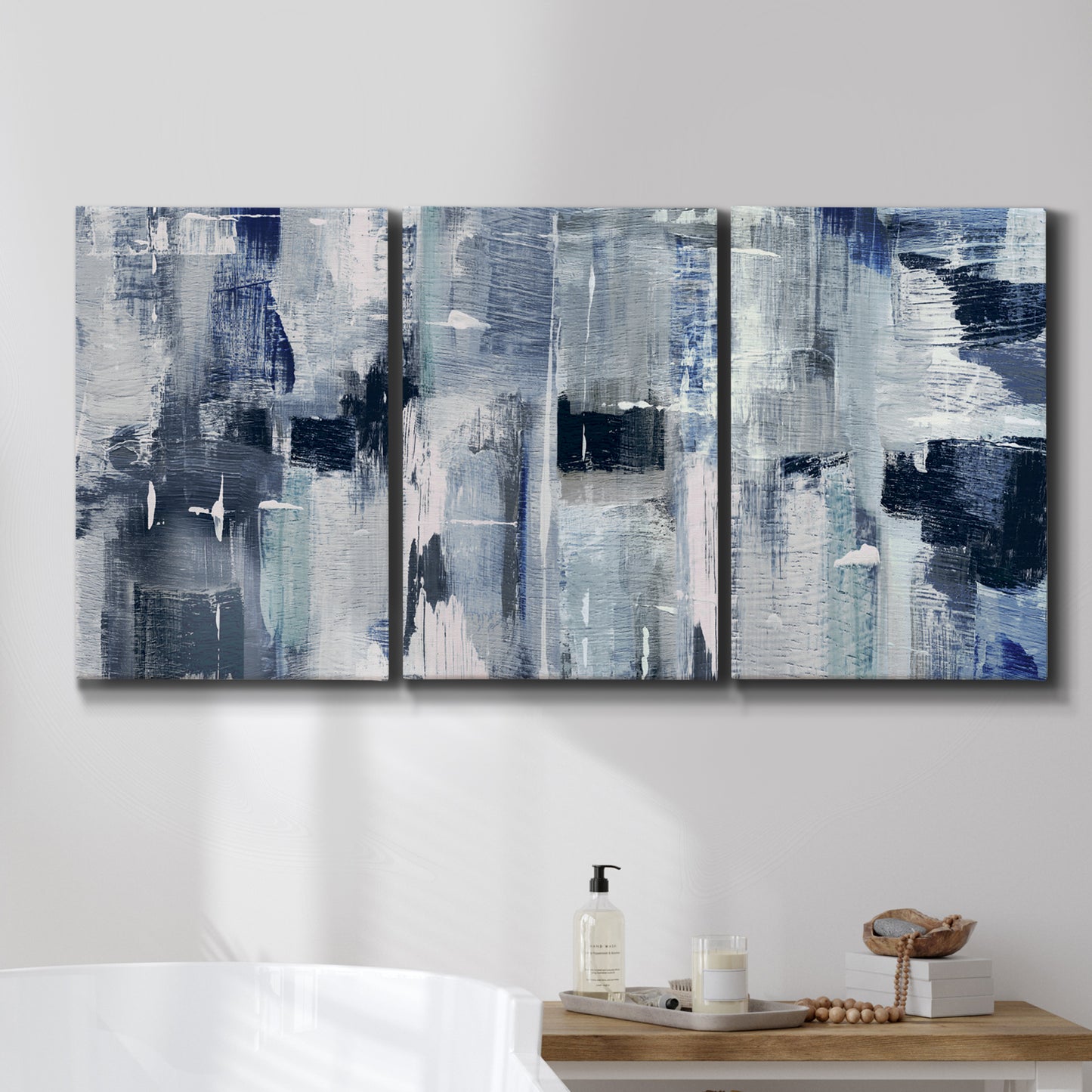 Three-panel canvas wall art featuring soft abstract mountain color fields, displayed in a bathroom above a bathtub.