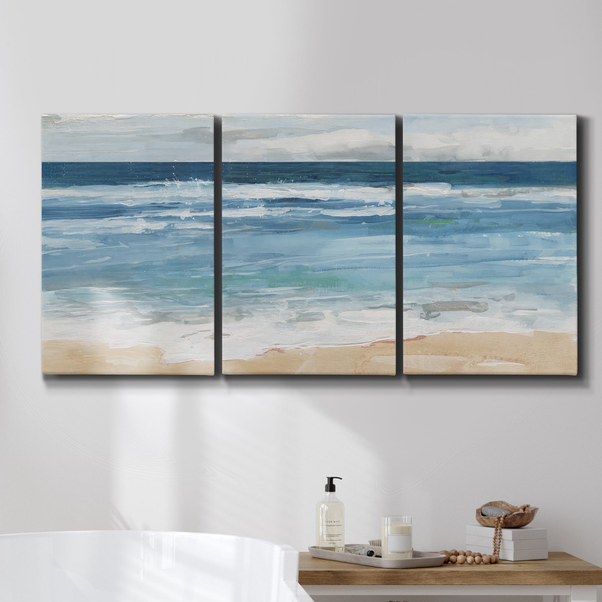 Three-panel canvas wall art featuring rolling ocean waves near shore, displayed in a bathroom above a bathtub.