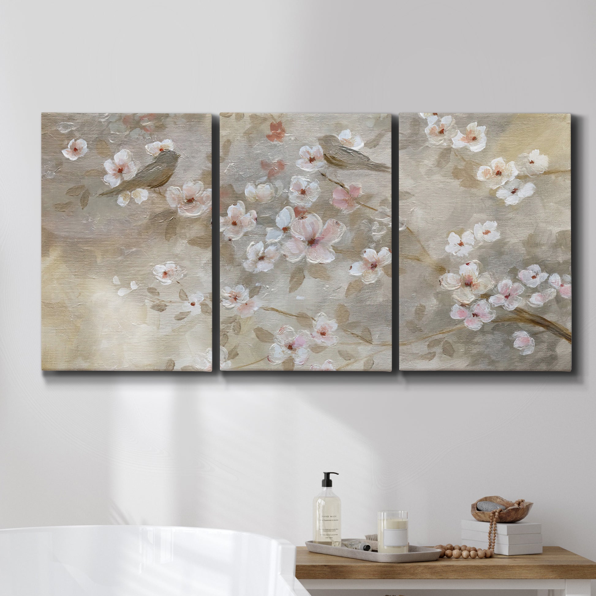 Three-panel canvas wall art featuring early spring blossoms in soft tones, displayed in a bathroom above a bathtub.