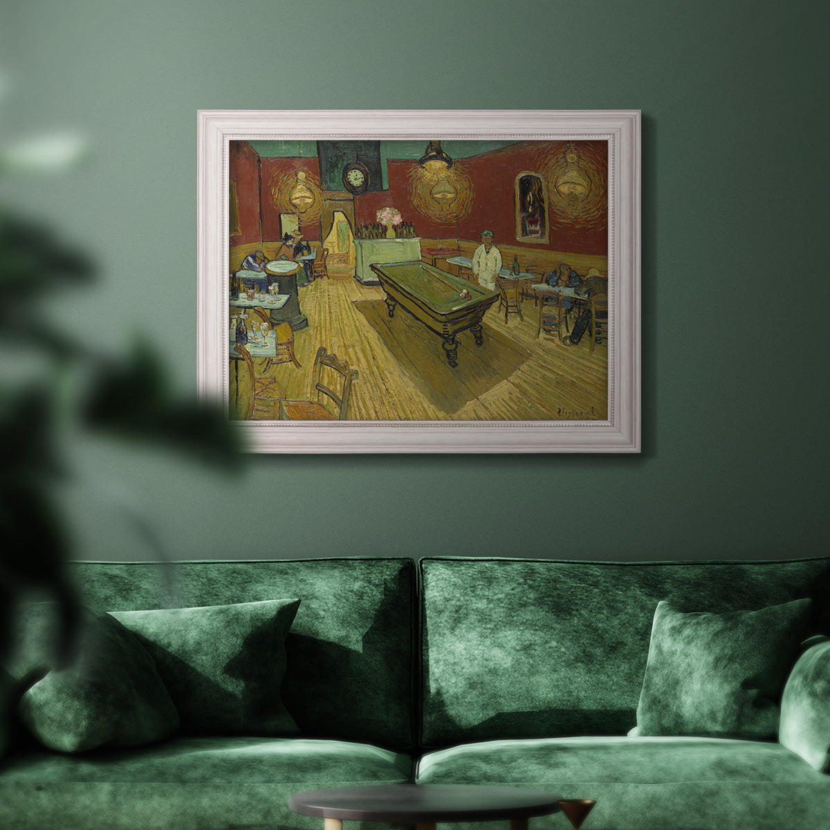 Impressionist interior of a night café by Vincent van Gogh in an ornate weathered white frame displayed in a dark-toned interior setting.