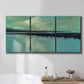 Three-panel canvas wall art featuring calm harbor water with glowing horizon, displayed in a bathroom above a bathtub.