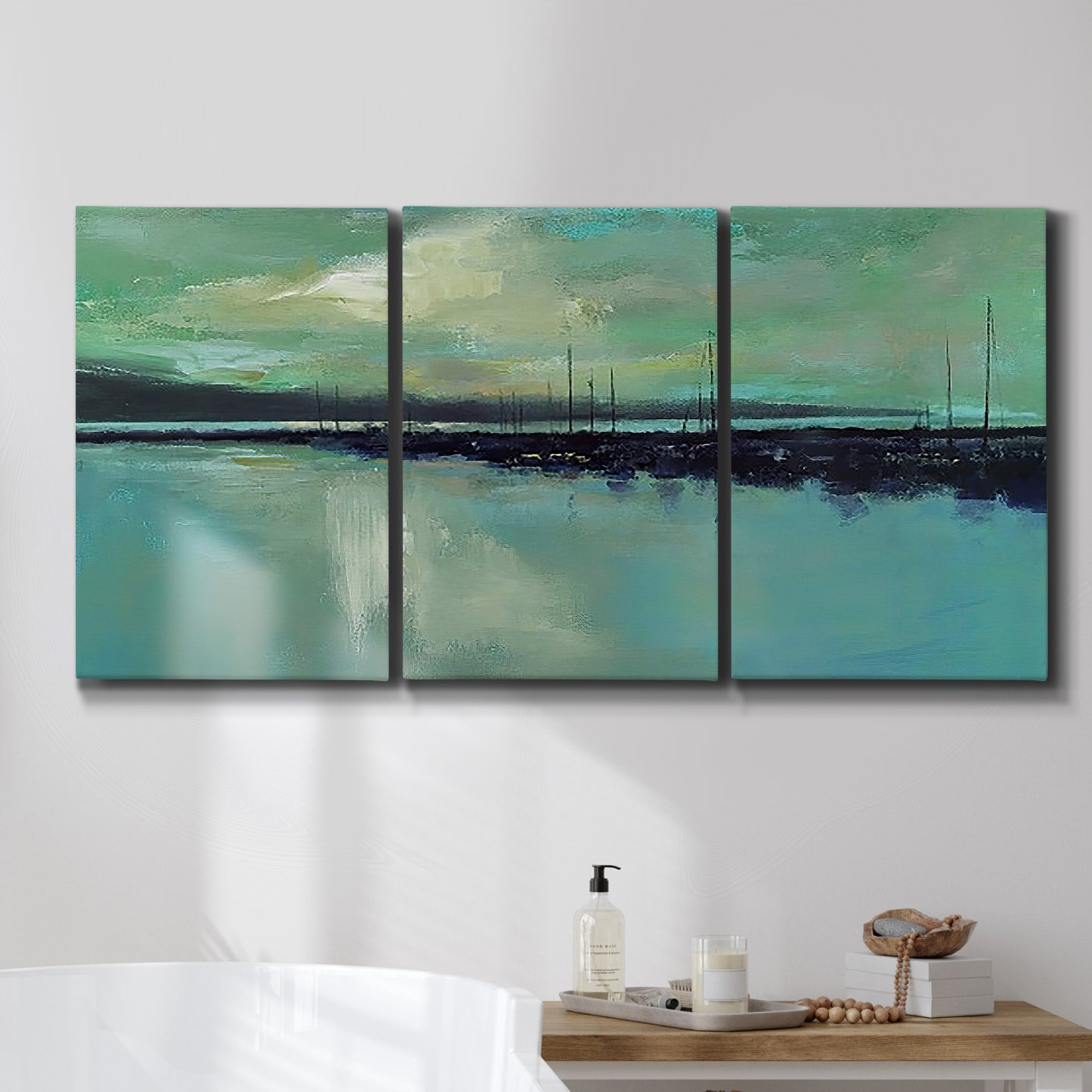 Three-panel canvas wall art featuring calm harbor water with glowing horizon, displayed in a bathroom above a bathtub.