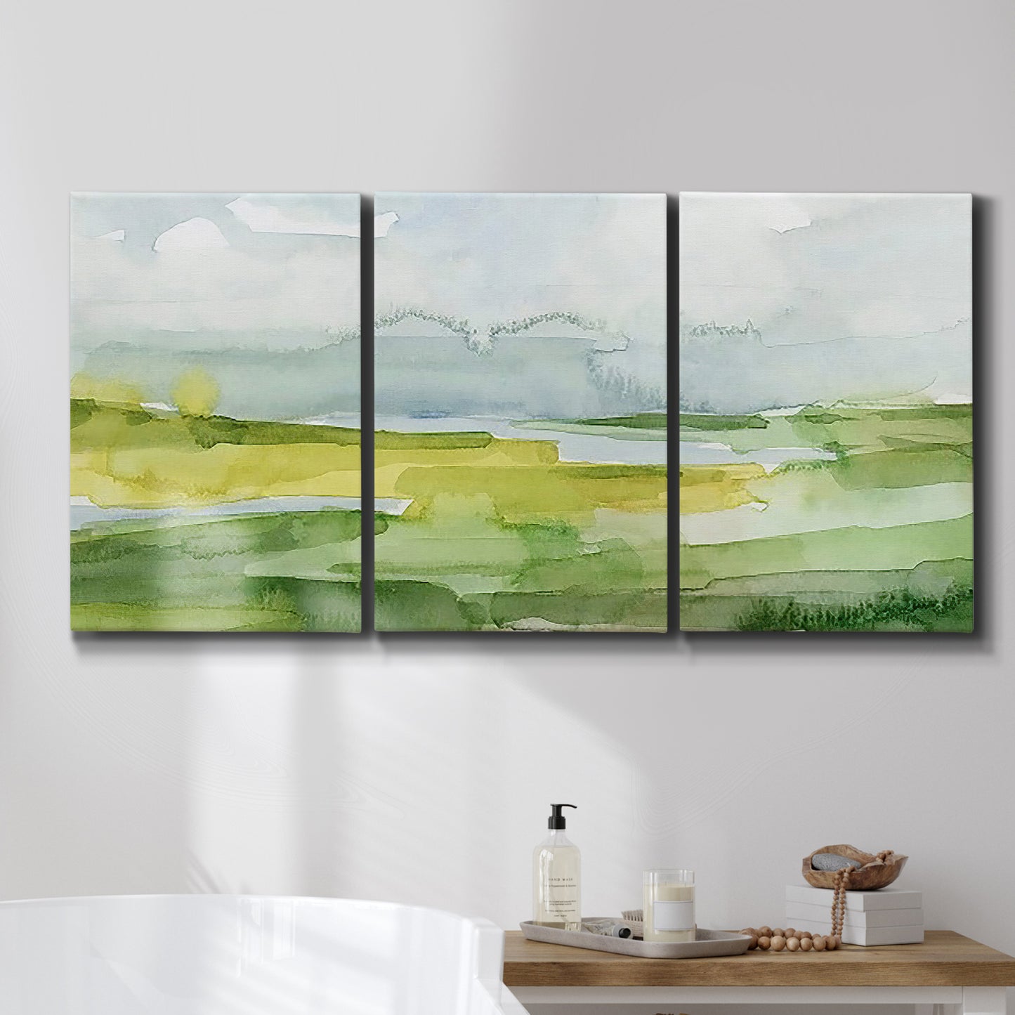 Three-panel canvas wall art featuring lowland wetlands with reflective water, displayed in a bathroom above a bathtub.