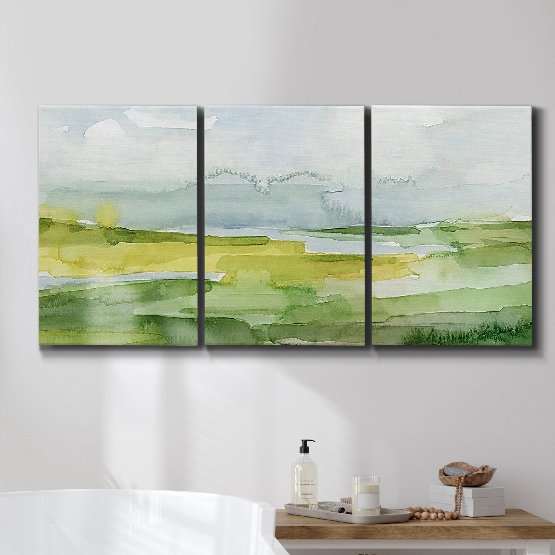 Three-panel canvas wall art featuring lowland wetlands with reflective water, displayed in a bathroom above a bathtub.