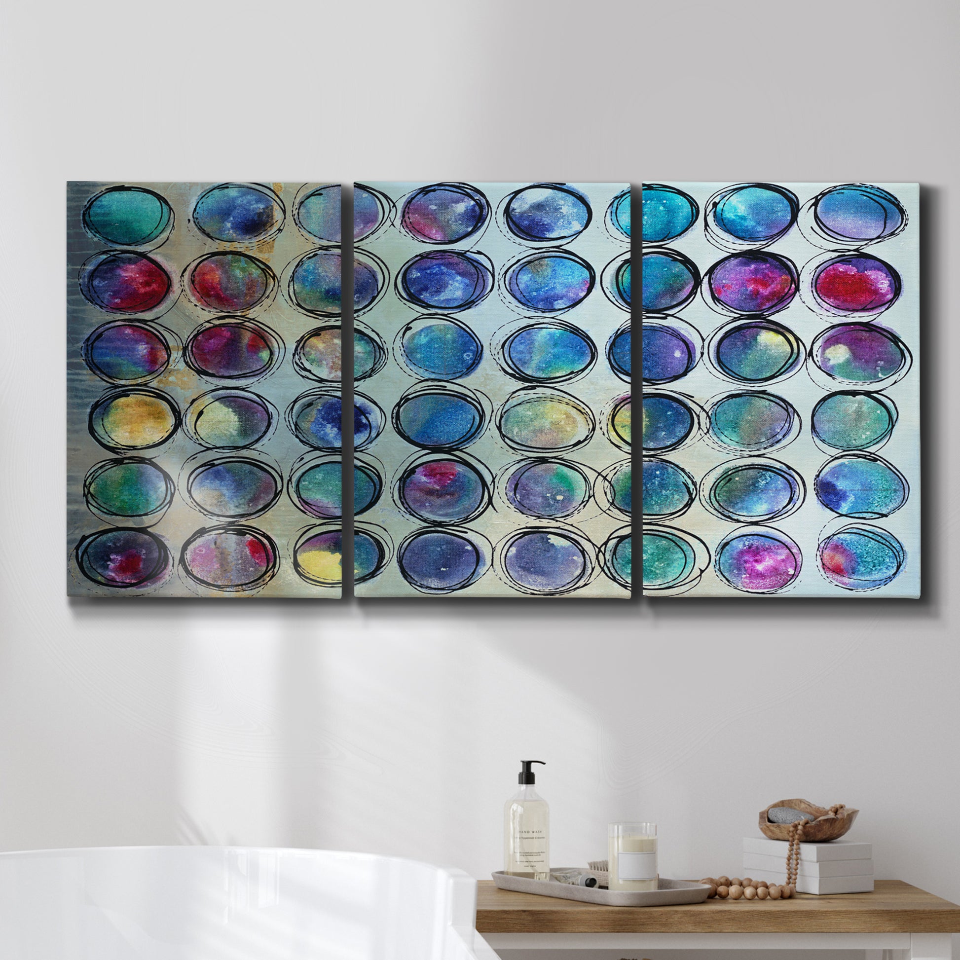 Three-panel canvas wall art featuring contrasting geometric abstract variations, displayed in a bathroom above a bathtub.