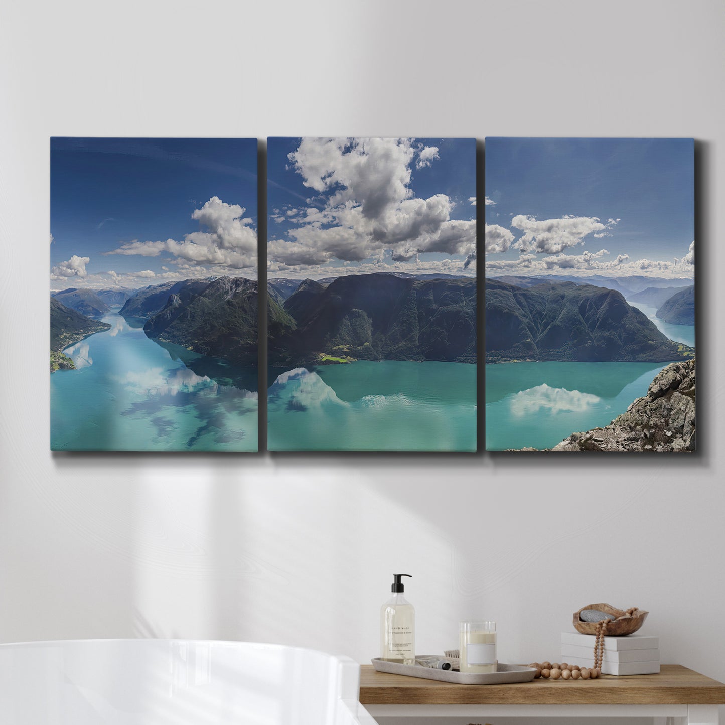 Three-panel canvas wall art featuring tropical water reflections with foliage, displayed in a bathroom above a bathtub.