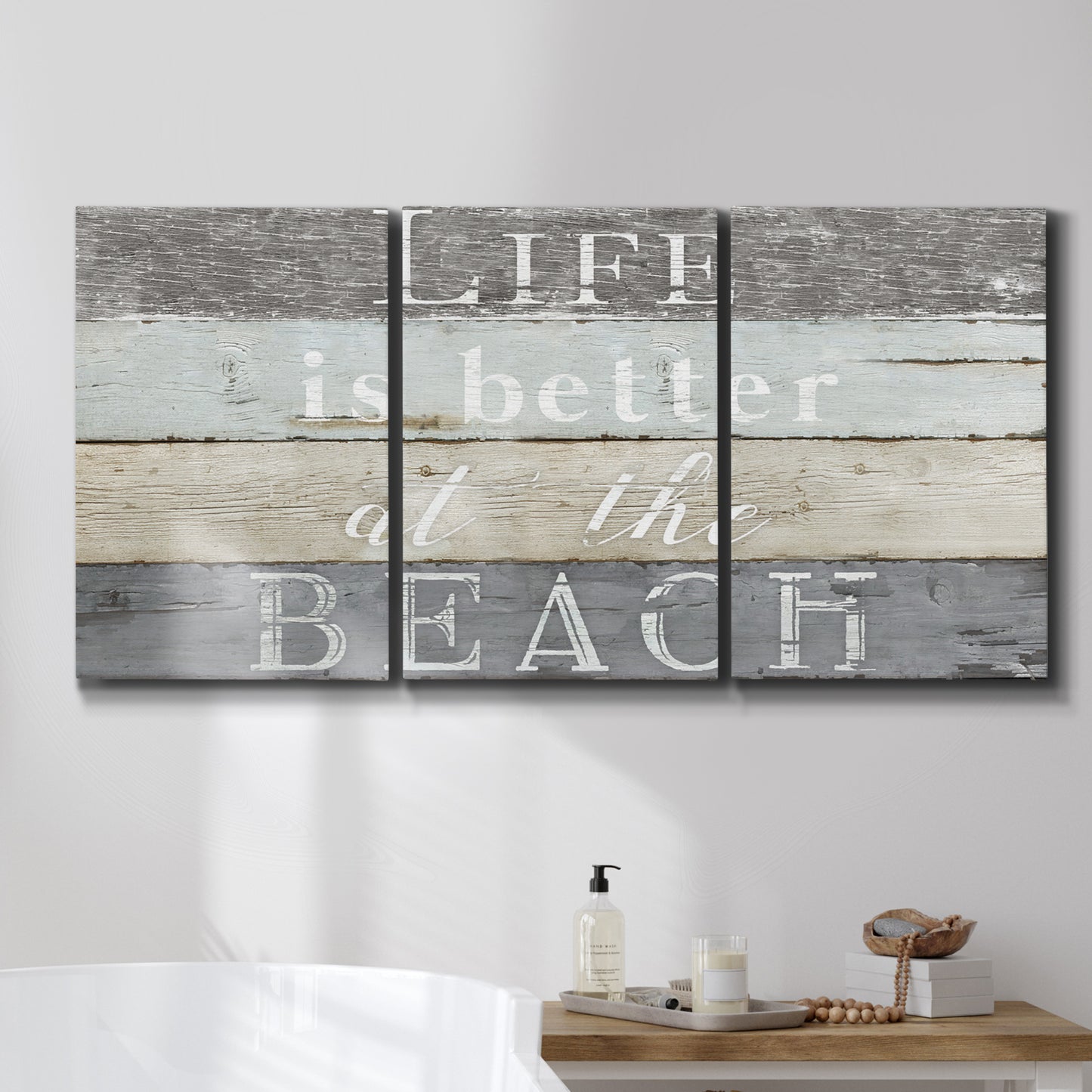 Three-panel canvas wall art featuring beach themed typography design, displayed in a bathroom above a bathtub.
