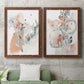 Set of two maple barnwood framed canvas prints depicting a coordinated art pair of loose blush gray and coral floral gestures rendered as abstract watercolor botanicals above a sofa in a modern living room.
