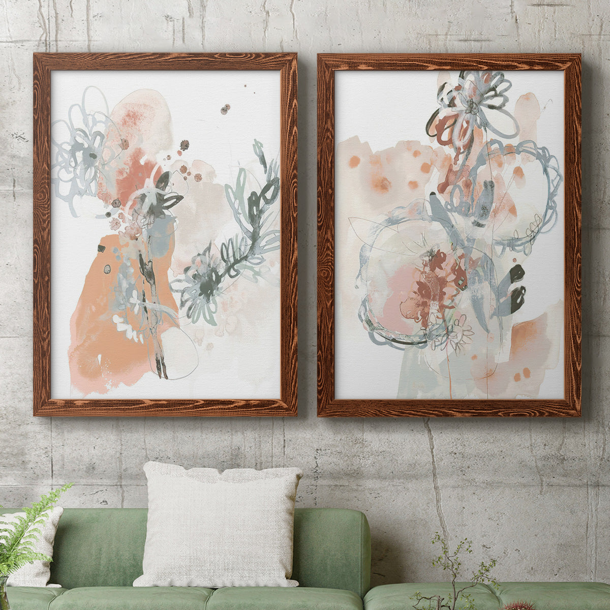 Set of two maple barnwood framed canvas prints depicting a coordinated art pair of loose blush gray and coral floral gestures rendered as abstract watercolor botanicals above a sofa in a modern living room.
