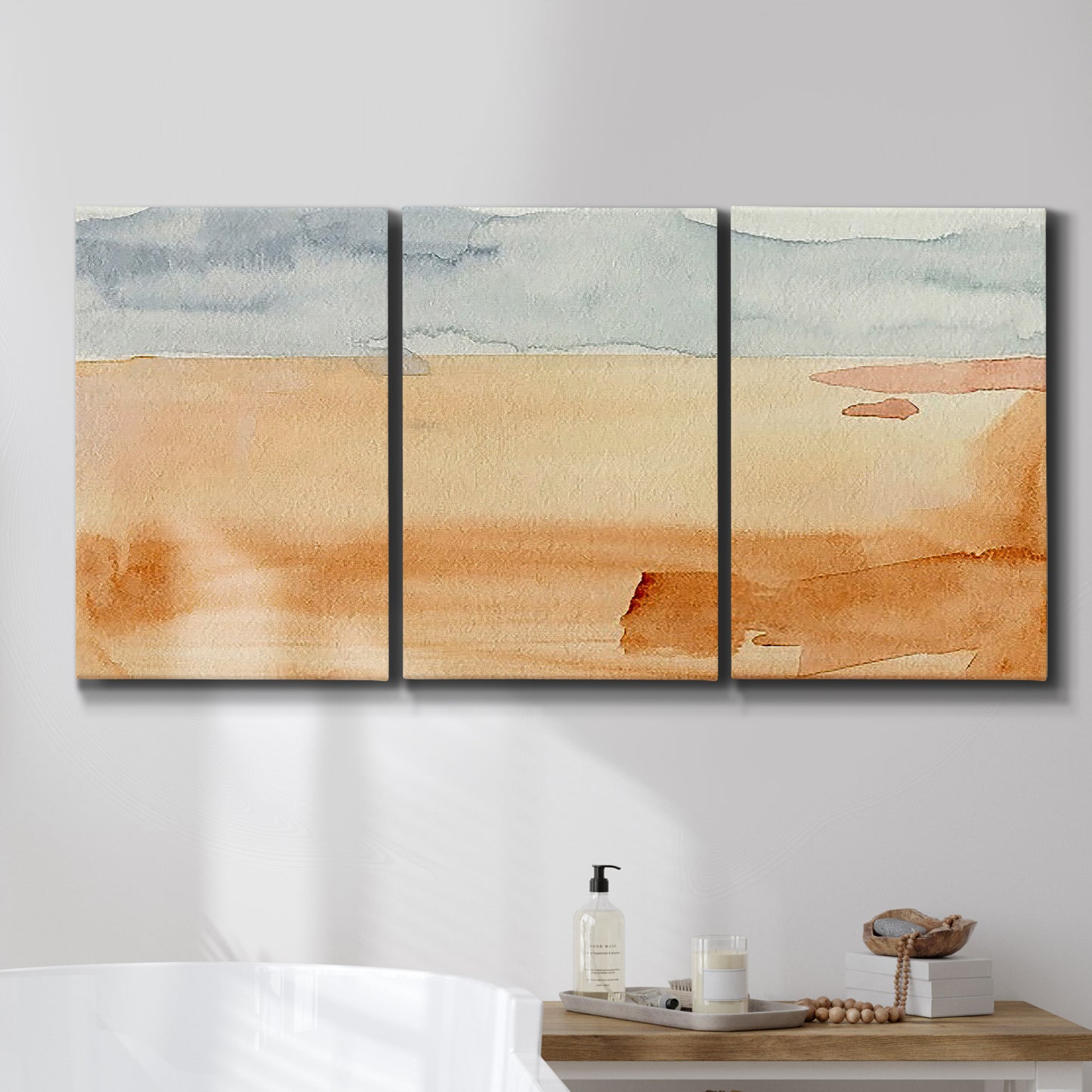 Three-panel canvas wall art featuring minimal horizon with soft blue tones, displayed in a bathroom above a bathtub.