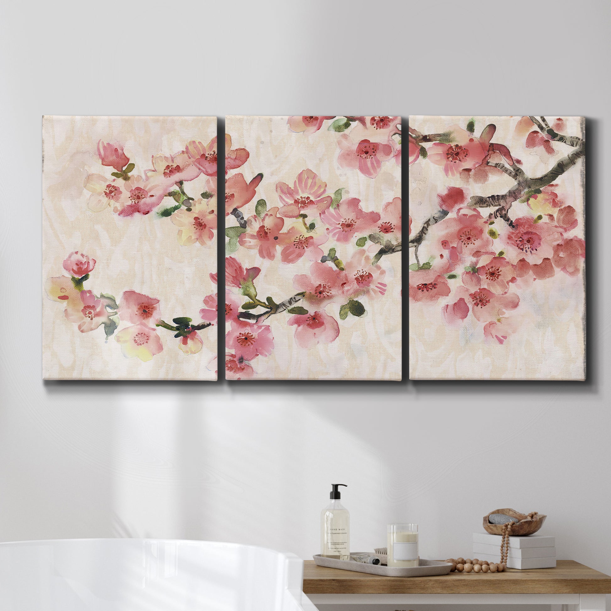 Three-panel canvas wall art featuring blooming cherry blossom branches, displayed in a bathroom above a bathtub.
