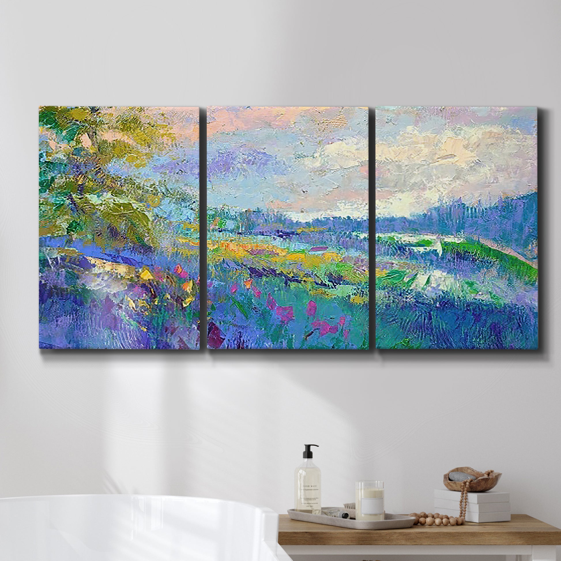 Three-panel canvas wall art featuring cheerful landscape under open sky, displayed in a bathroom above a bathtub.