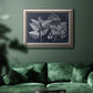 Decorative botanical foliage drawing on navy background in an ornate vintage silver frame displayed in a dark-toned interior setting.