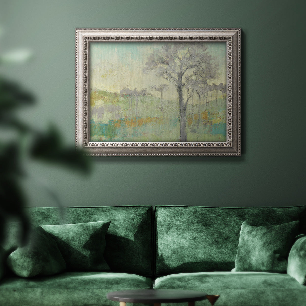 Classical watercolor landscape with trees in an ornate vintage silver frame displayed in a dark-toned interior setting.