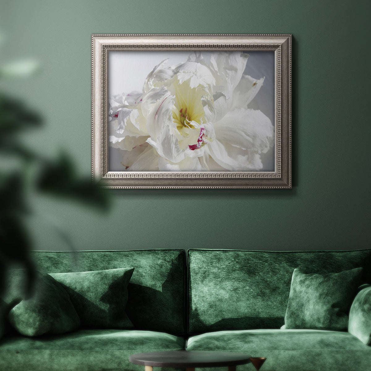 Soft white peony close-up in an ornate vintage silver frame displayed in a dark-toned interior setting.