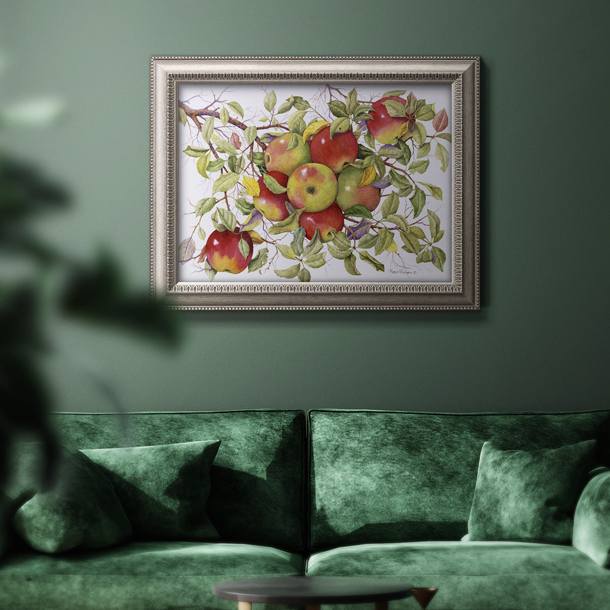 Classic still life painting of apples in an ornate vintage silver frame displayed in a dark-toned interior setting.