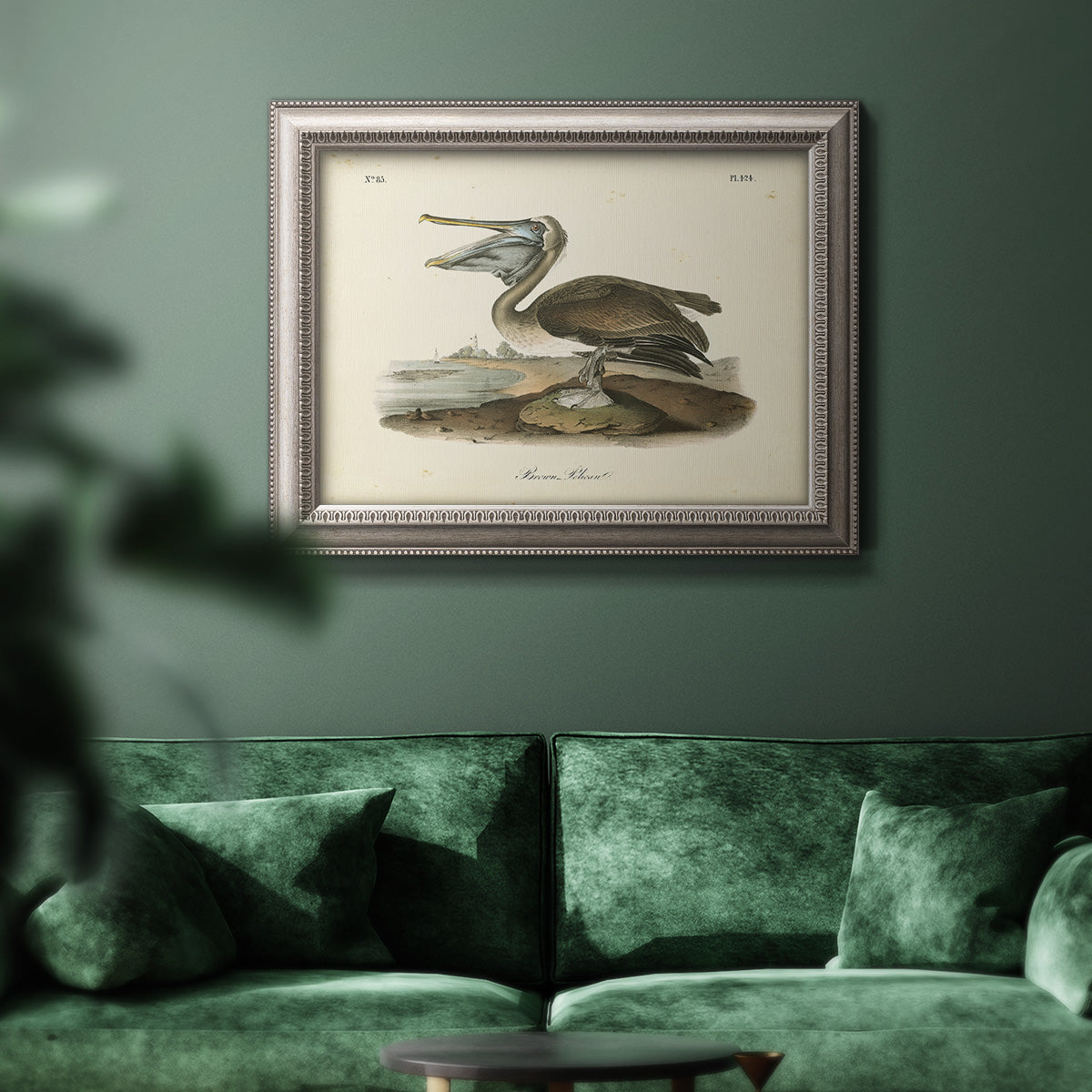 Antique brown pelican bird illustration by John James Audubon in an ornate vintage silver frame displayed in a dark-toned interior setting.