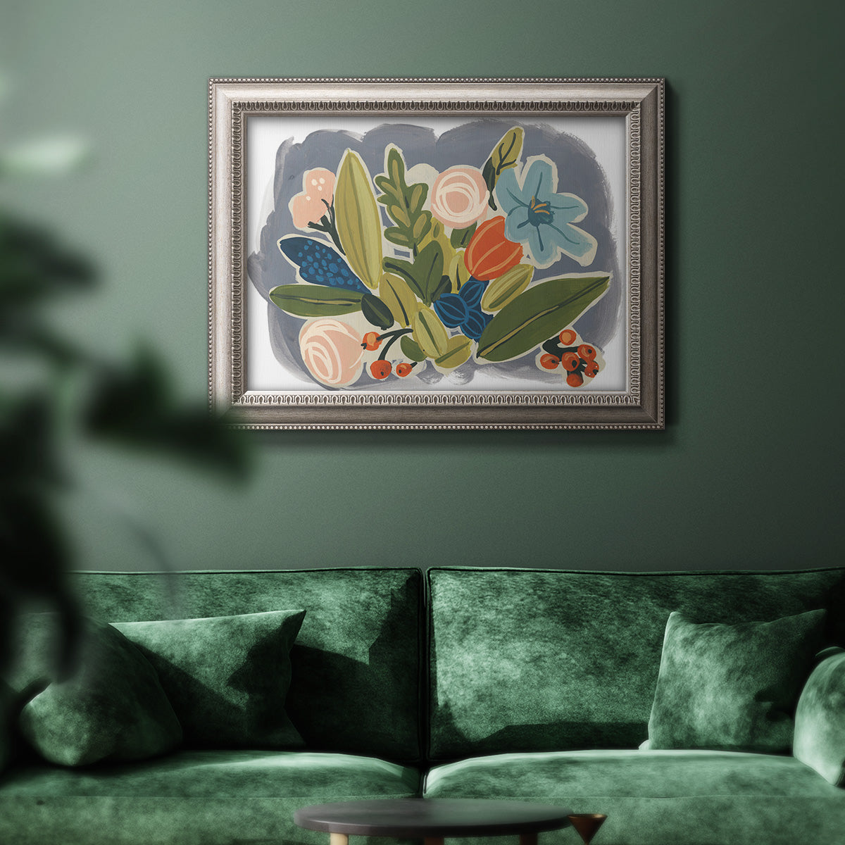 Colorful eclectic botanical artwork in an ornate vintage silver frame displayed in a dark-toned interior setting.