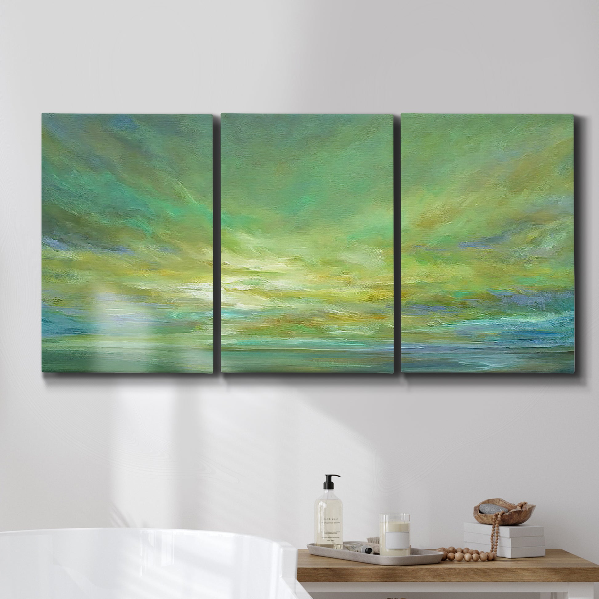 Three-panel canvas wall art featuring coastal shoreline under open sky, displayed in a bathroom above a bathtub.