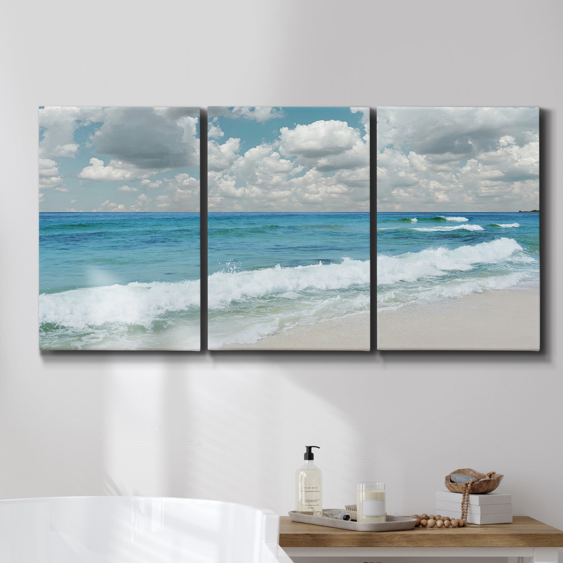 Three-panel canvas wall art featuring tropical beach scene with turquoise water, displayed in a bathroom above a bathtub.
