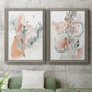 Set of two gray barnwood framed canvas prints depicting a coordinated art pair of loose blush gray and coral floral gestures rendered as abstract watercolor botanicals above a sofa in a modern living room.