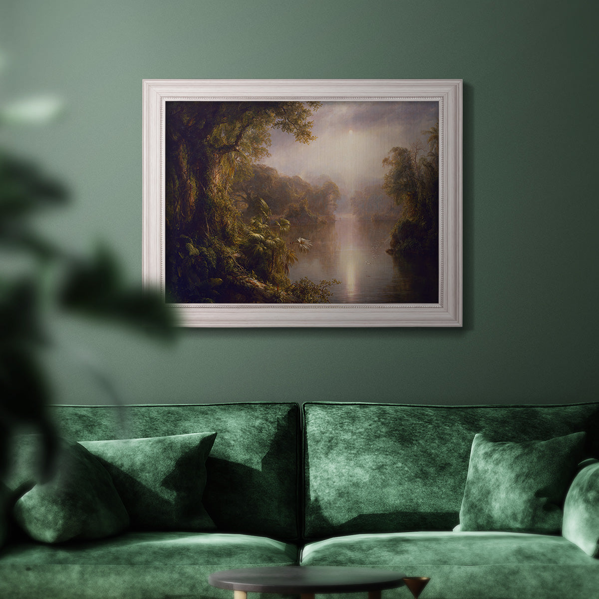 Luminous romantic landscape painting by Frederic Edwin Church in an ornate champagne frame displayed in a dark-toned interior setting.