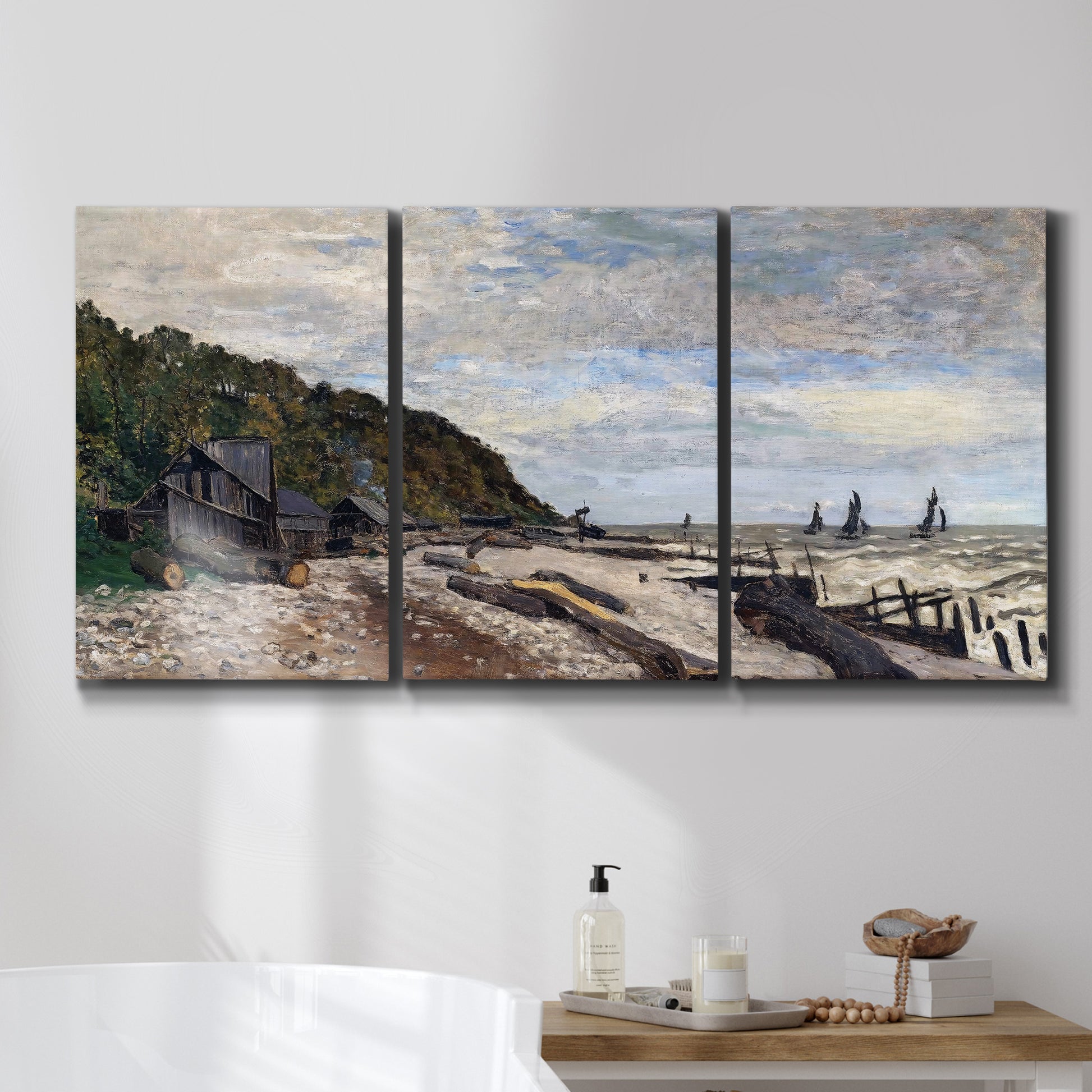 Three-panel canvas wall art featuring open sea along rocky shore, displayed in a bathroom above a bathtub.