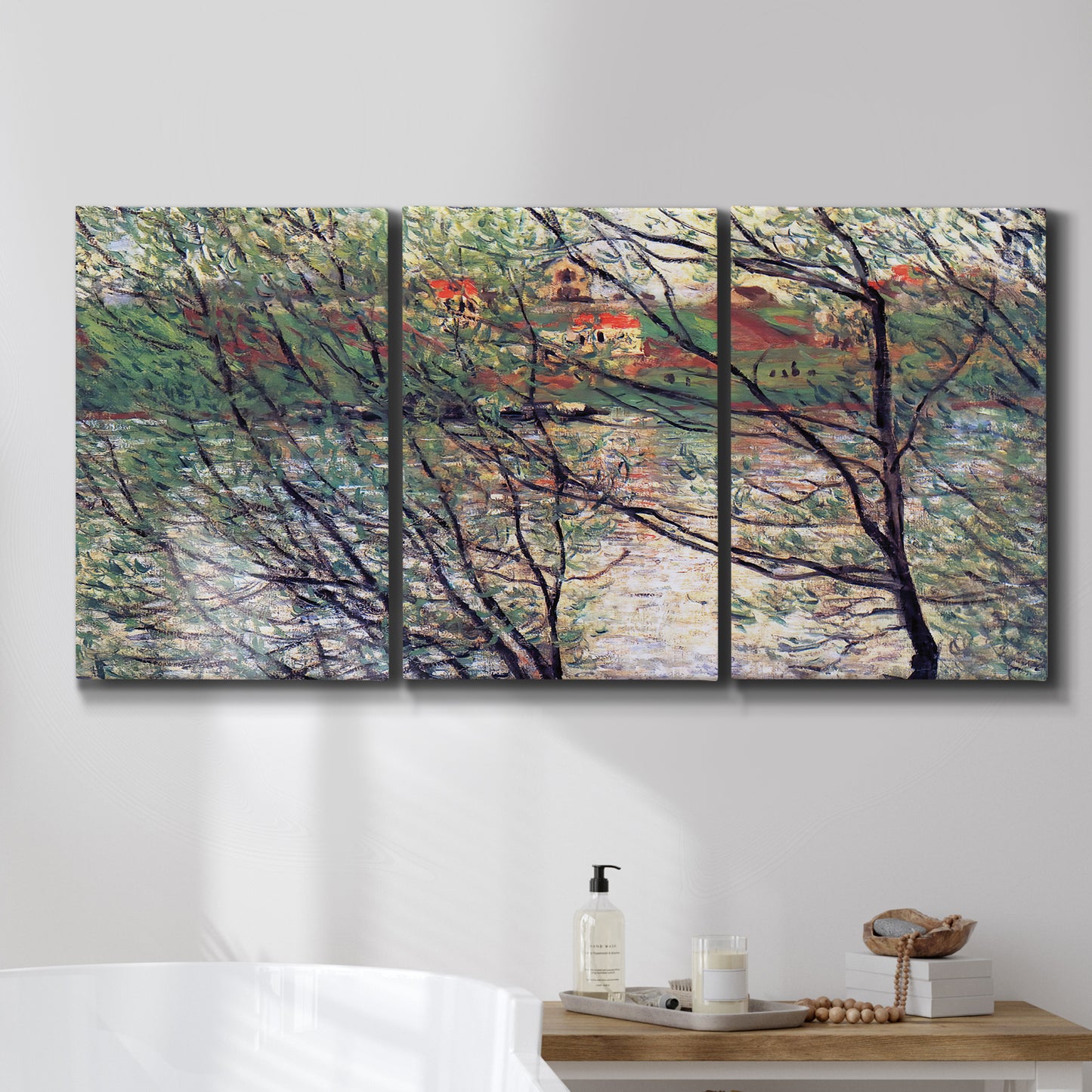 Three-panel canvas wall art featuring riverside park with figures and trees, displayed in a bathroom above a bathtub.